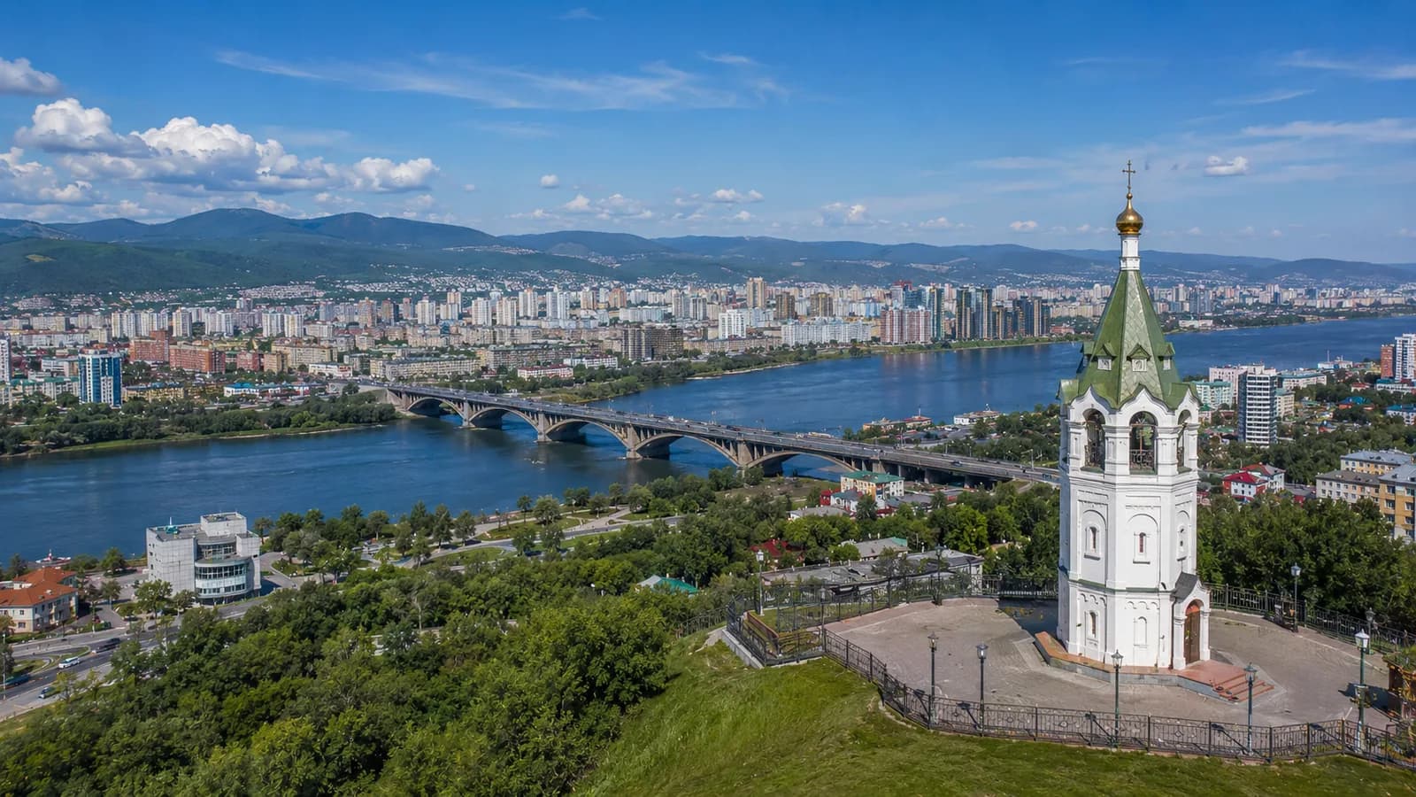 Часовня Параскевы Пятницы на Караульной горе в Красноярске, вид с высоты на Енисей с мостом, плотную городскую застройку и сопки на горизонте